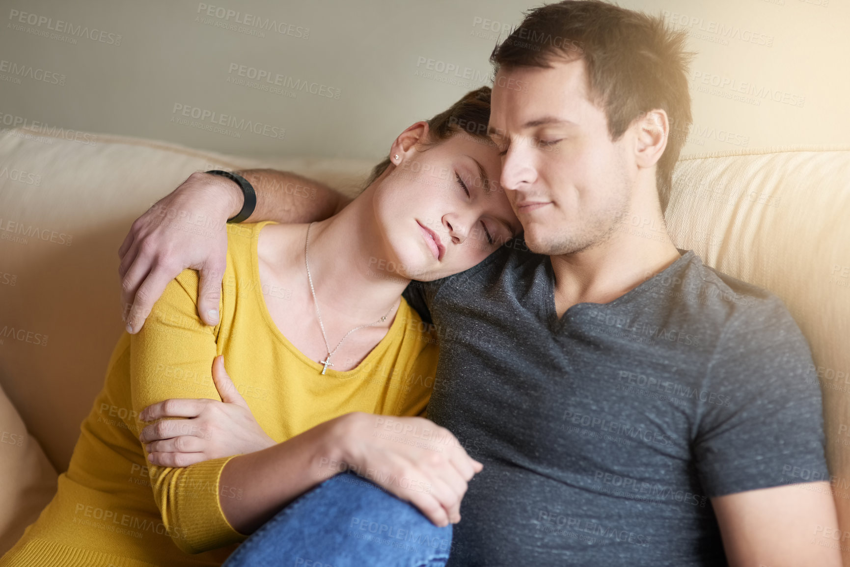 Buy stock photo Shot of a tired couple cuddling together on the couch at home