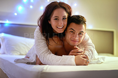 Buy stock photo Portrait of a happy young couple lying on their bed together