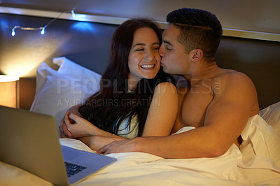 Buy stock photo Shot of an affectionate young couple using a laptop together in bed