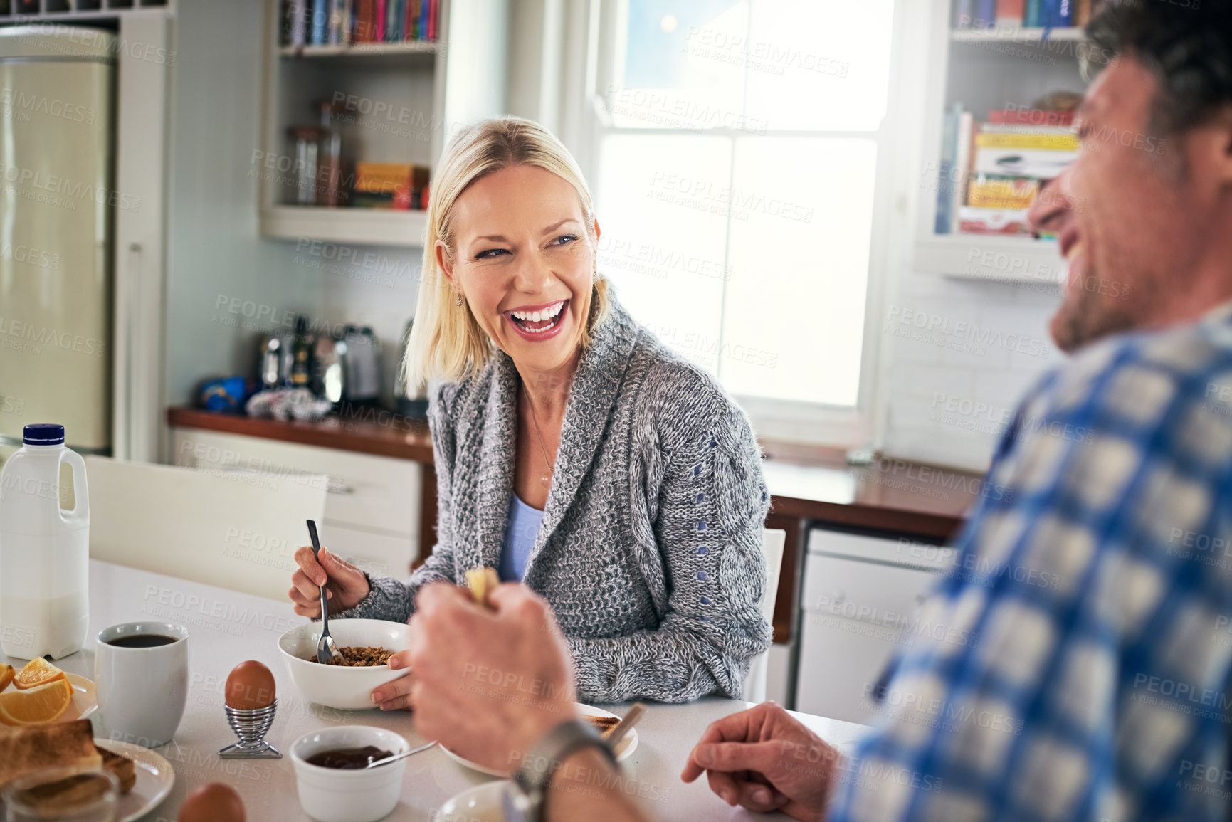 Buy stock photo Couple, breakfast and eating while laughing at table, love and care for fiber of meal in home. Happy people, cereal and snack for breakfast and comedy for bonding, nutrition and joke in marriage