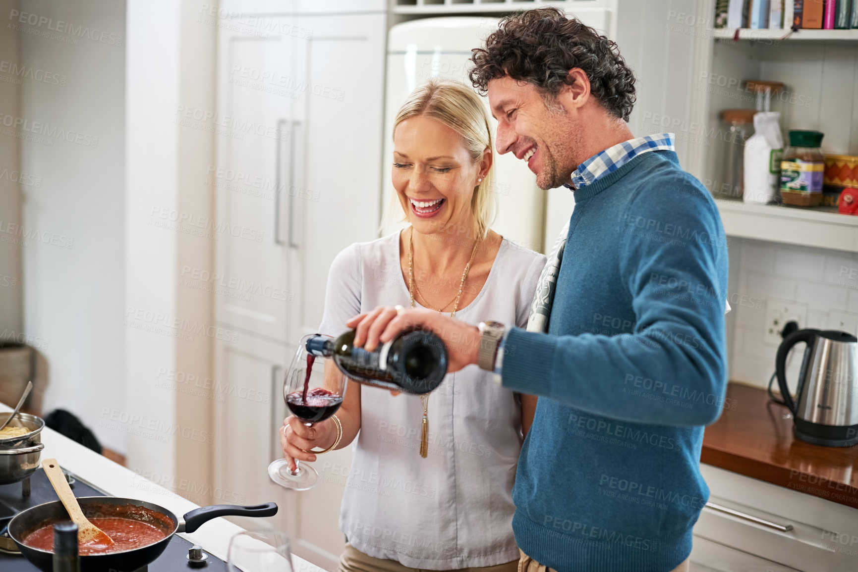 Buy stock photo Couple, stove and pour wine for drinking in home, love and care for food or meal in kitchen. Happy people, alcohol and pan for cooking sauce and laugh for bonding, nutrition and support in marriage
