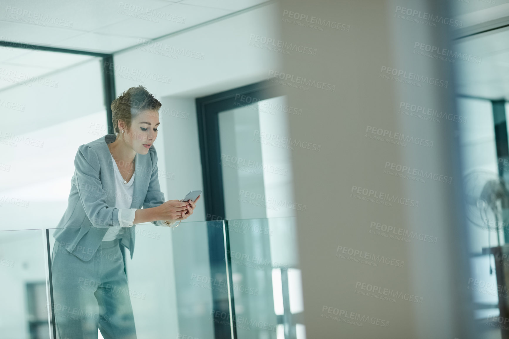 Buy stock photo Cropped shot of a young businesswoman texting on a cellphone in an office