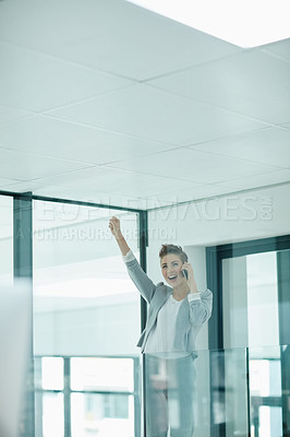 Buy stock photo Cropped shot of a young businesswoman doing a fist pump while talking on a cellphone in an office