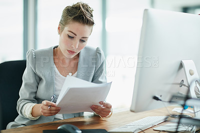 Buy stock photo Cropped shot of a young businesswoman reading some paperwork in an office