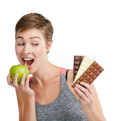 Buy stock photo Studio shot of a fit young woman deciding whether to eat chocolate or an apple against a white background