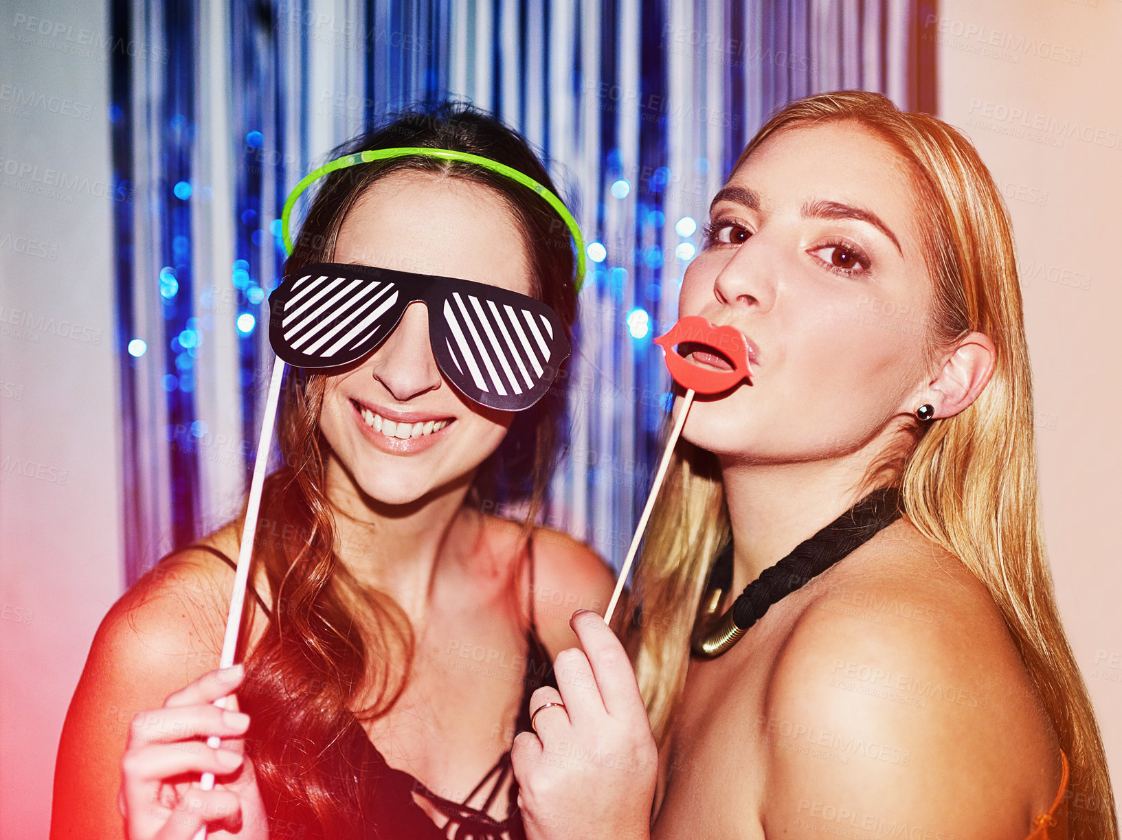 Buy stock photo Shot of two beautiful young women having fun with props in a photobooth