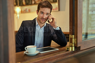 Buy stock photo Shot of a young businessman making a phonecall while sitting in a coffee shop