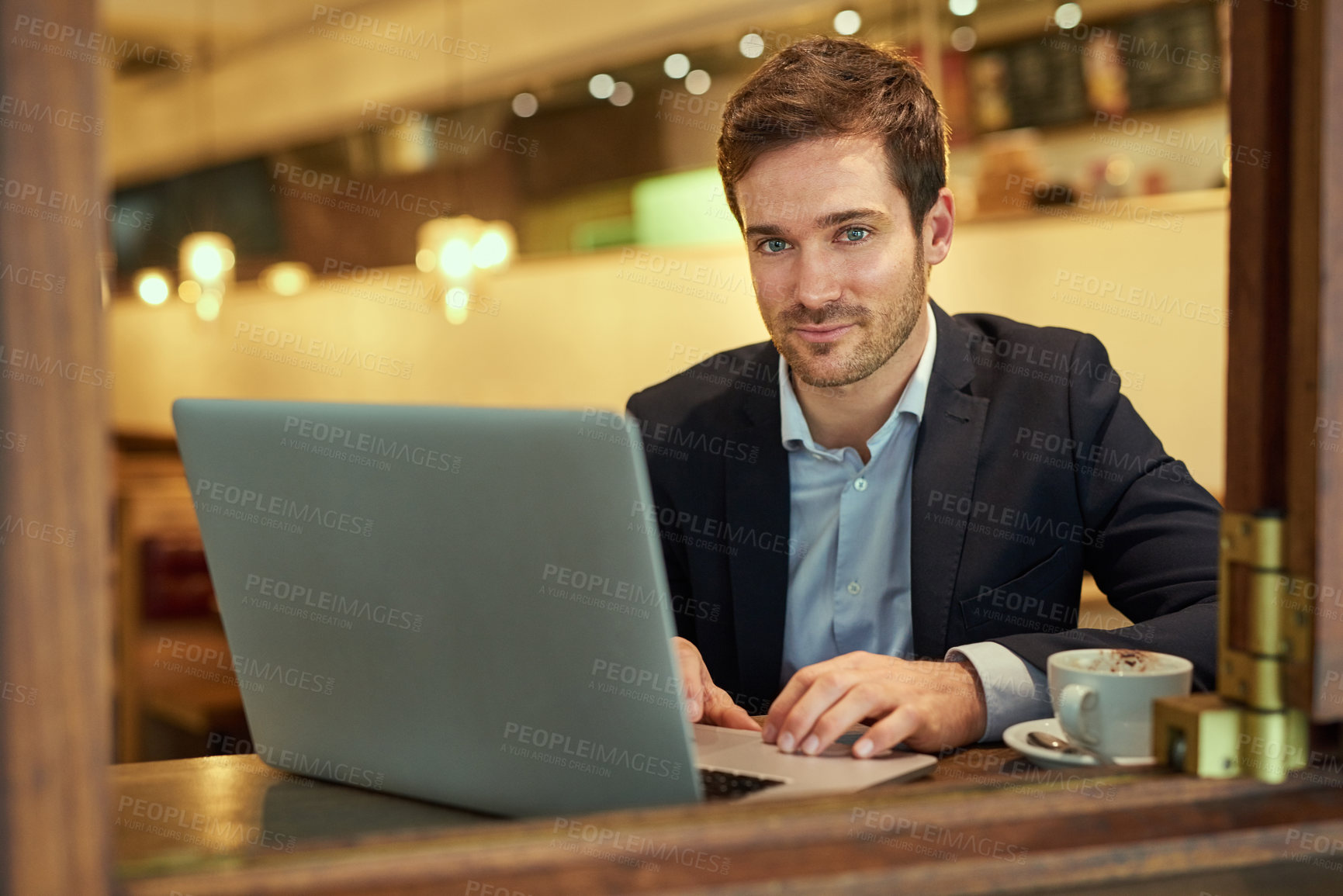Buy stock photo Portrait of a young businessman using his laptop while sitting in a coffee shop