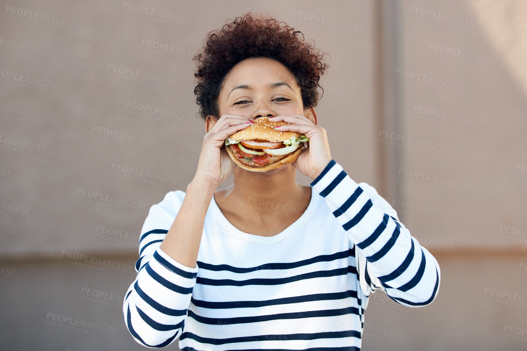 Buy stock photo Portrait of a young woman eating a hamburger
