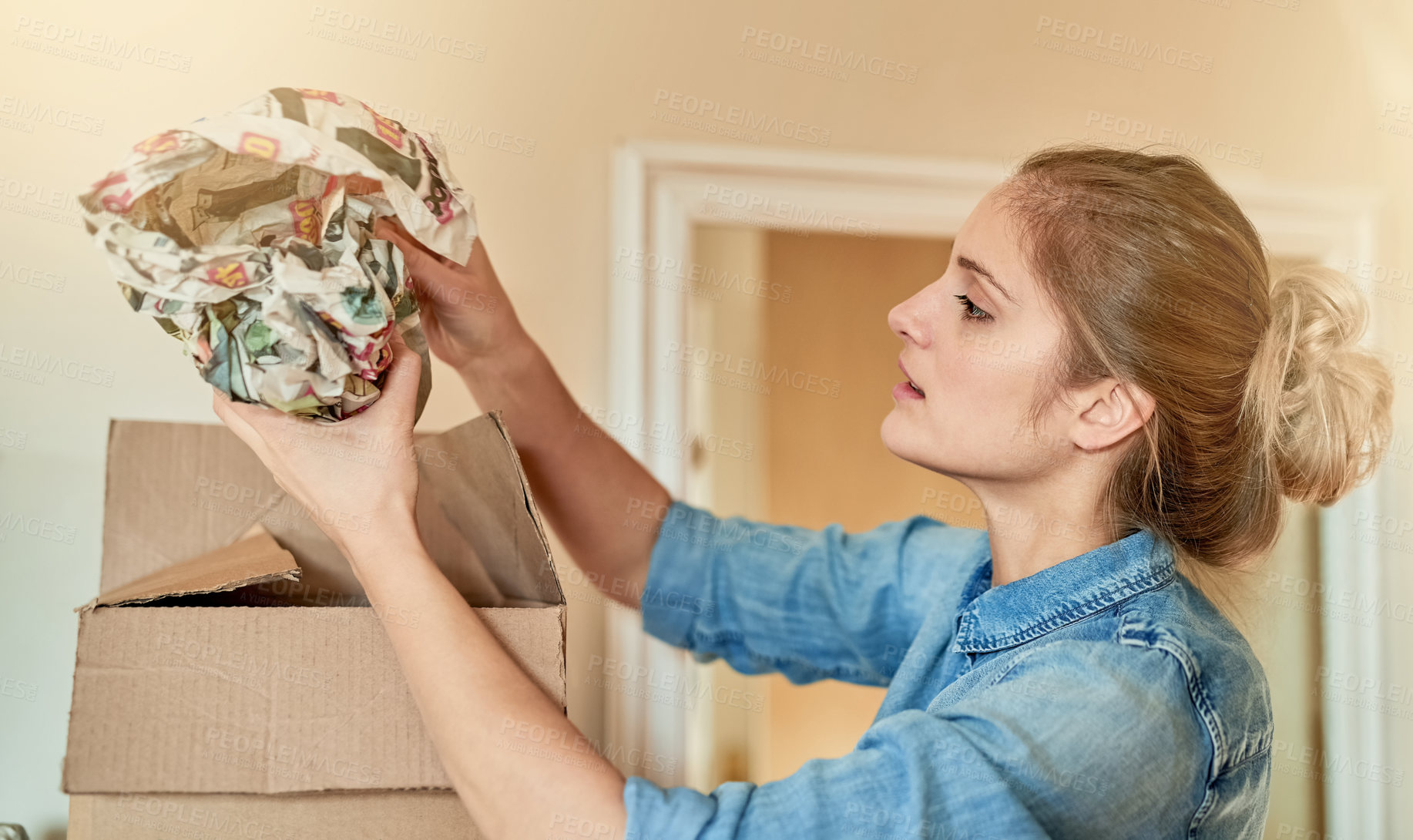 Buy stock photo Shot of a young woman unpacking a box at home