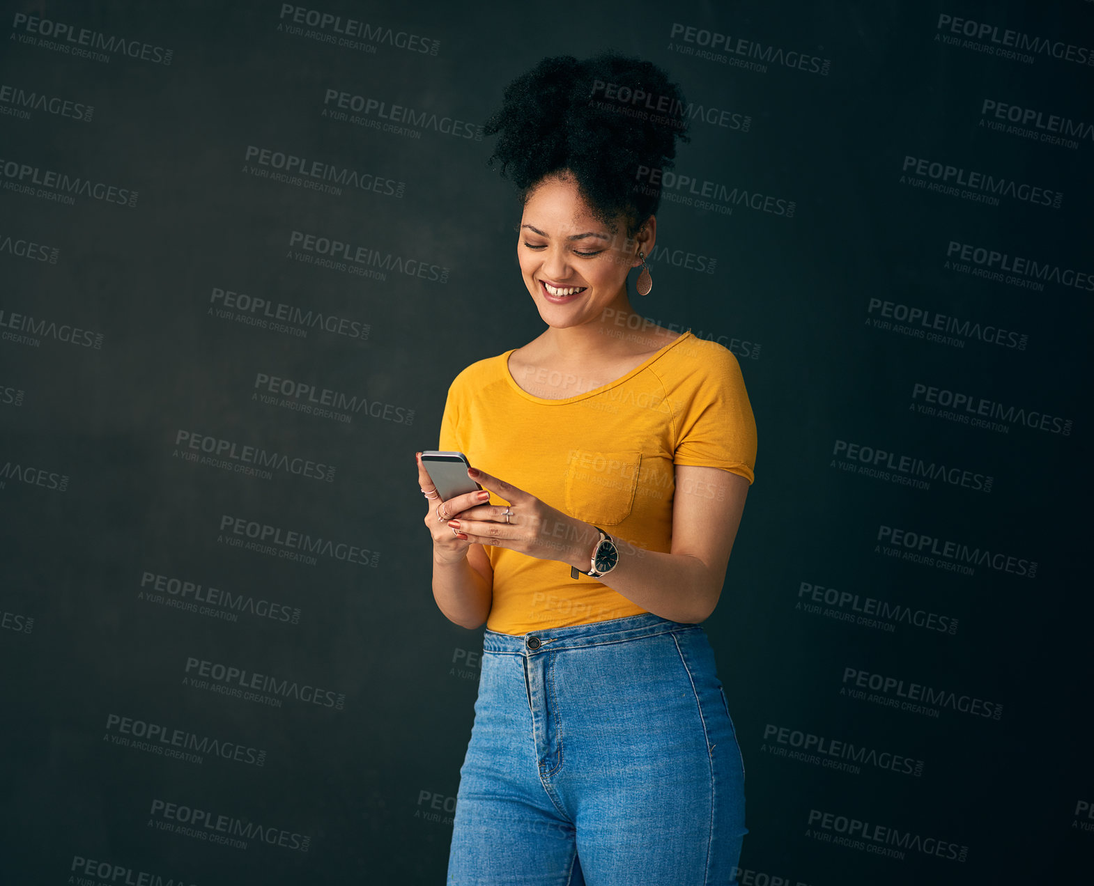 Buy stock photo Shot of a young woman holding a cellphone while posing against a grey background