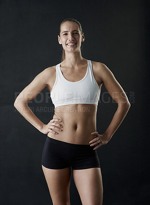 Buy stock photo Studio portrait of a sporty young woman standing against a dark background
