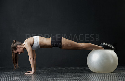 Buy stock photo Studio shot of an attractive young woman working out against a dark background