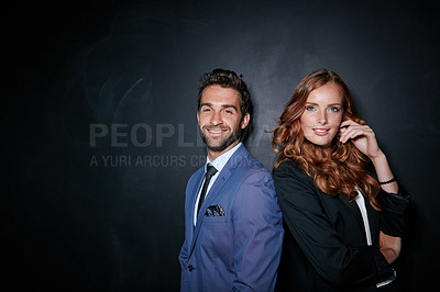 Buy stock photo Studio portrait of a young couple standing against a dark background
