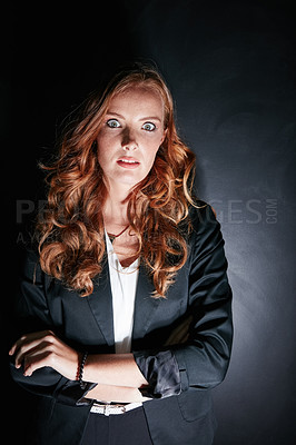 Buy stock photo Studio portrait of a worried looking young woman standing against a dark background