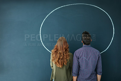 Buy stock photo Rearview shot of a young couple looking at an empty circle drawn on a blackboard