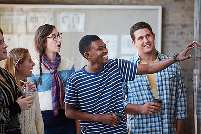 Buy stock photo Cropped shot of a group of university students looking at a notice on a wall