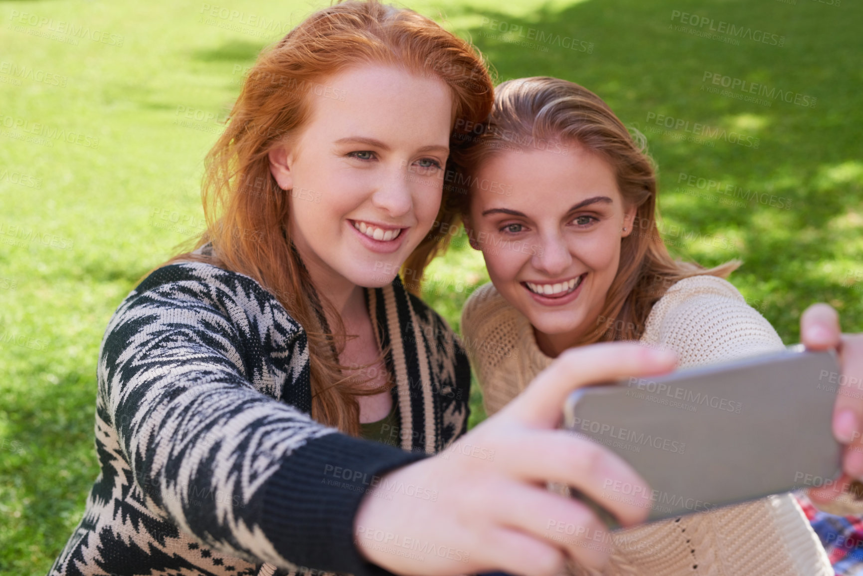 Buy stock photo Shot of two young friends taking a selfie together with a phone