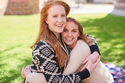 Buy stock photo Shot of two happy friends hugging outdoors
