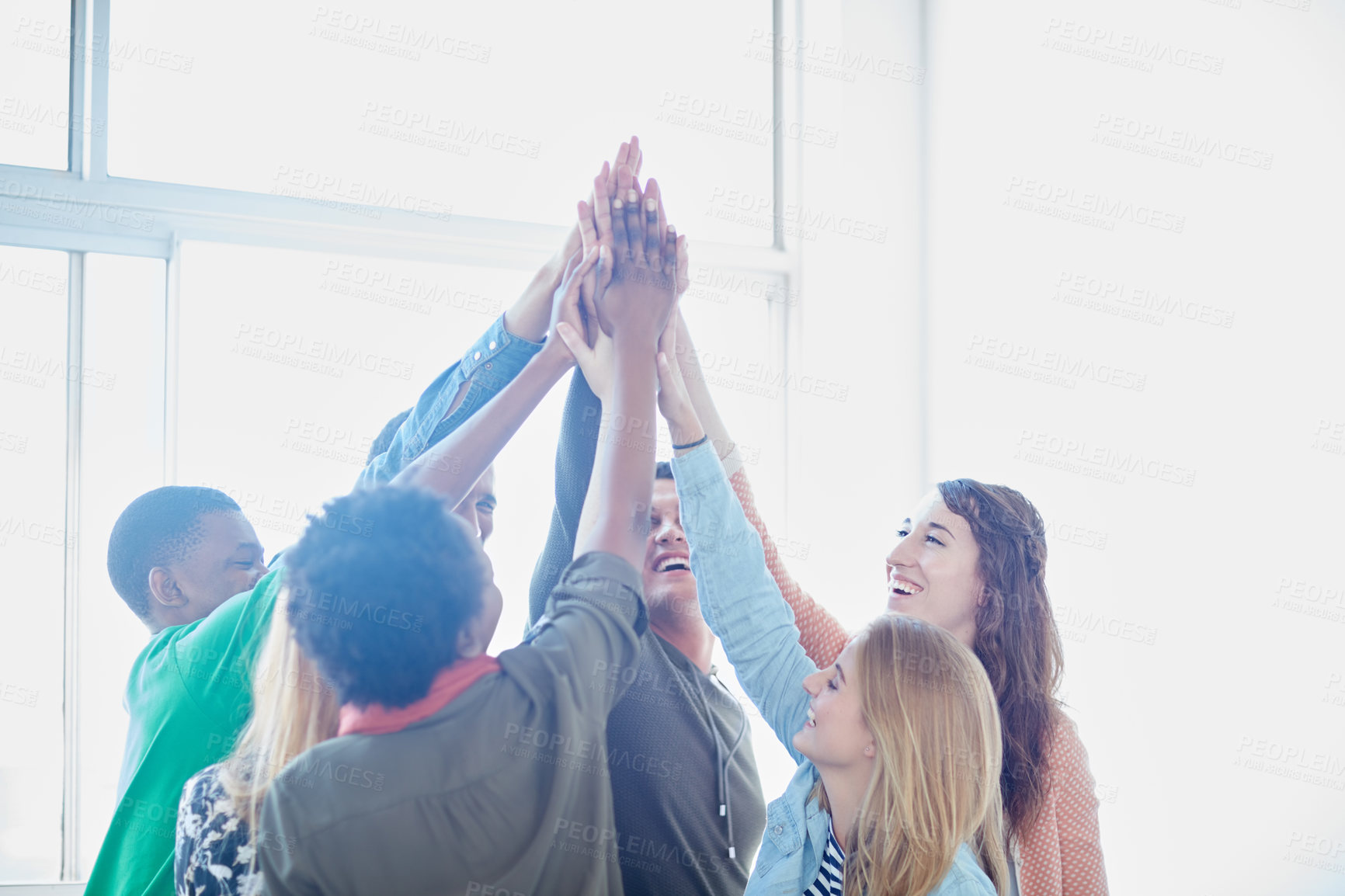 Buy stock photo Shot of a group of university students high fiving one another during class