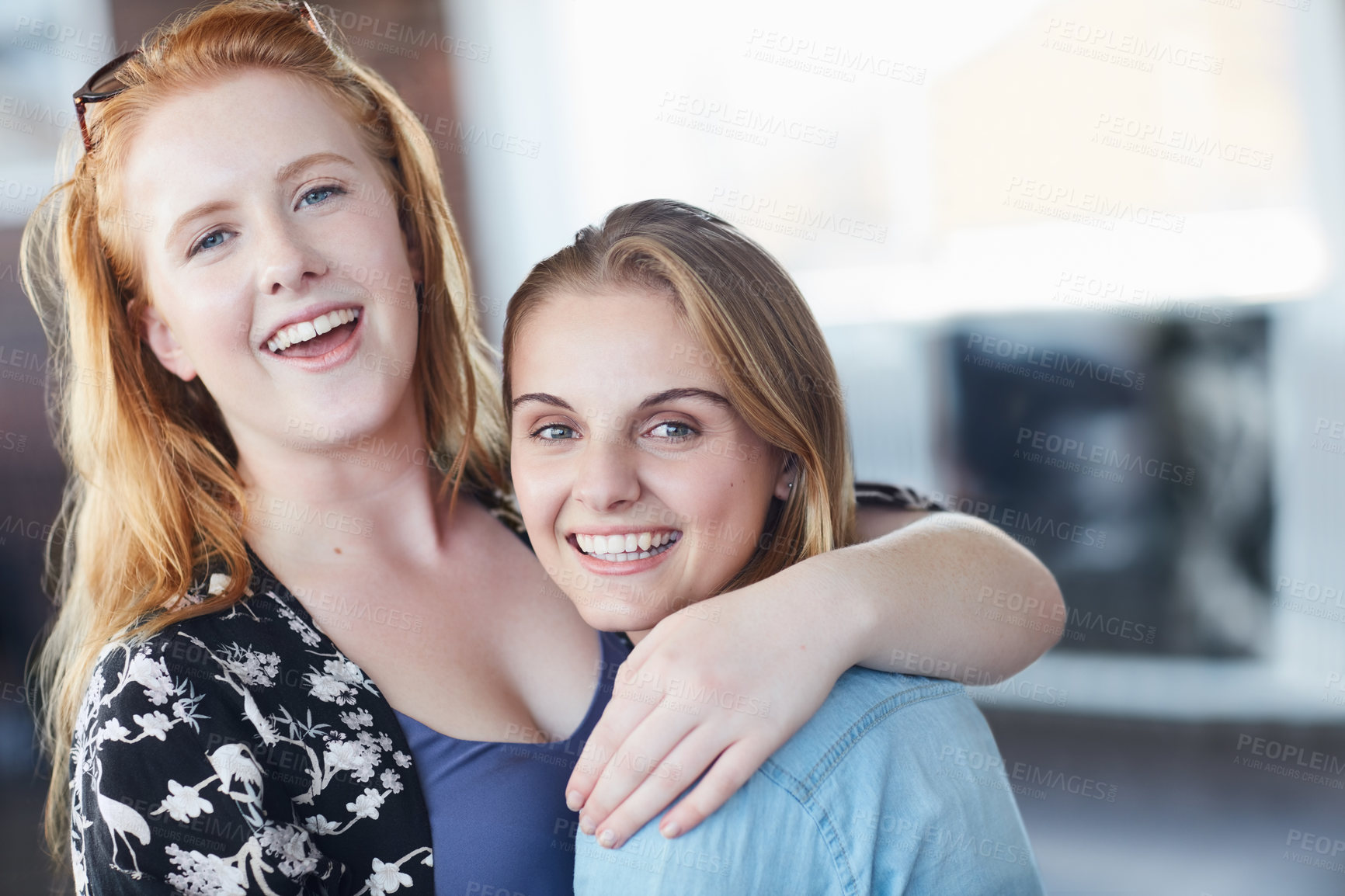 Buy stock photo Portrait of two university students embracing while standing in their classroom
