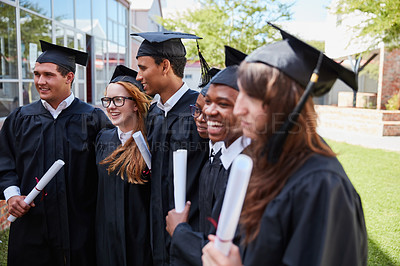 Buy stock photo Shot of a happy group of students standing outside on their graduation day