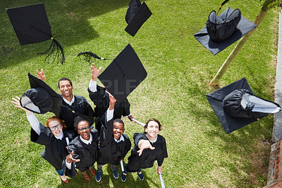 Buy stock photo High angle shot of a group of students throwing their caps into the air on graduation day