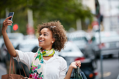 Buy stock photo Shot of an attractive young woman taking a selfie while on a shopping spree in the city