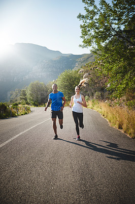 Buy stock photo Shot of a sporty couple out running on a mountain road