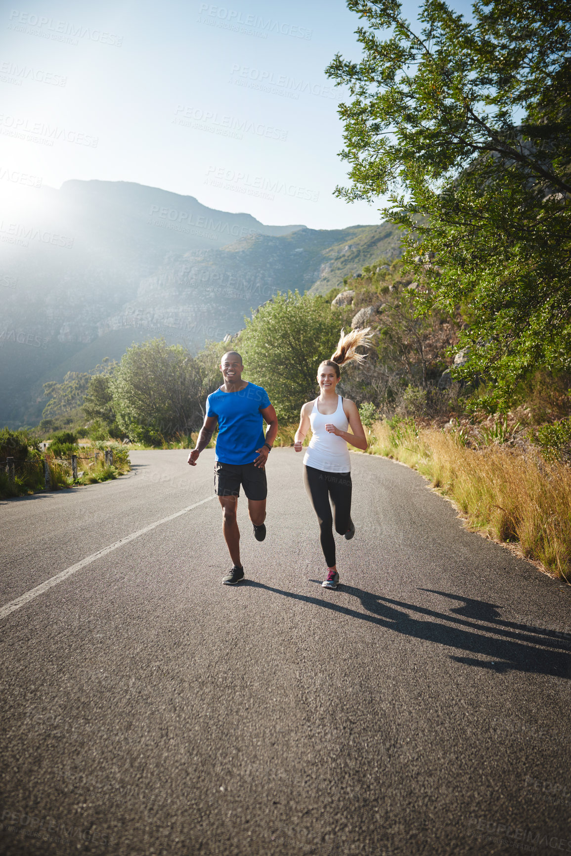 Buy stock photo Shot of a sporty couple out running on a mountain road