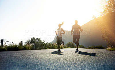 Buy stock photo Low angle shot of two people running on a tarmac road