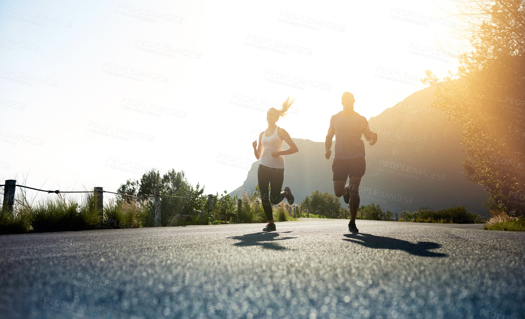 Buy stock photo Low angle shot of two people running on a tarmac road