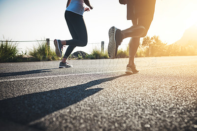 Buy stock photo Cropped shot of two unrecognizable people running on a tarmac road