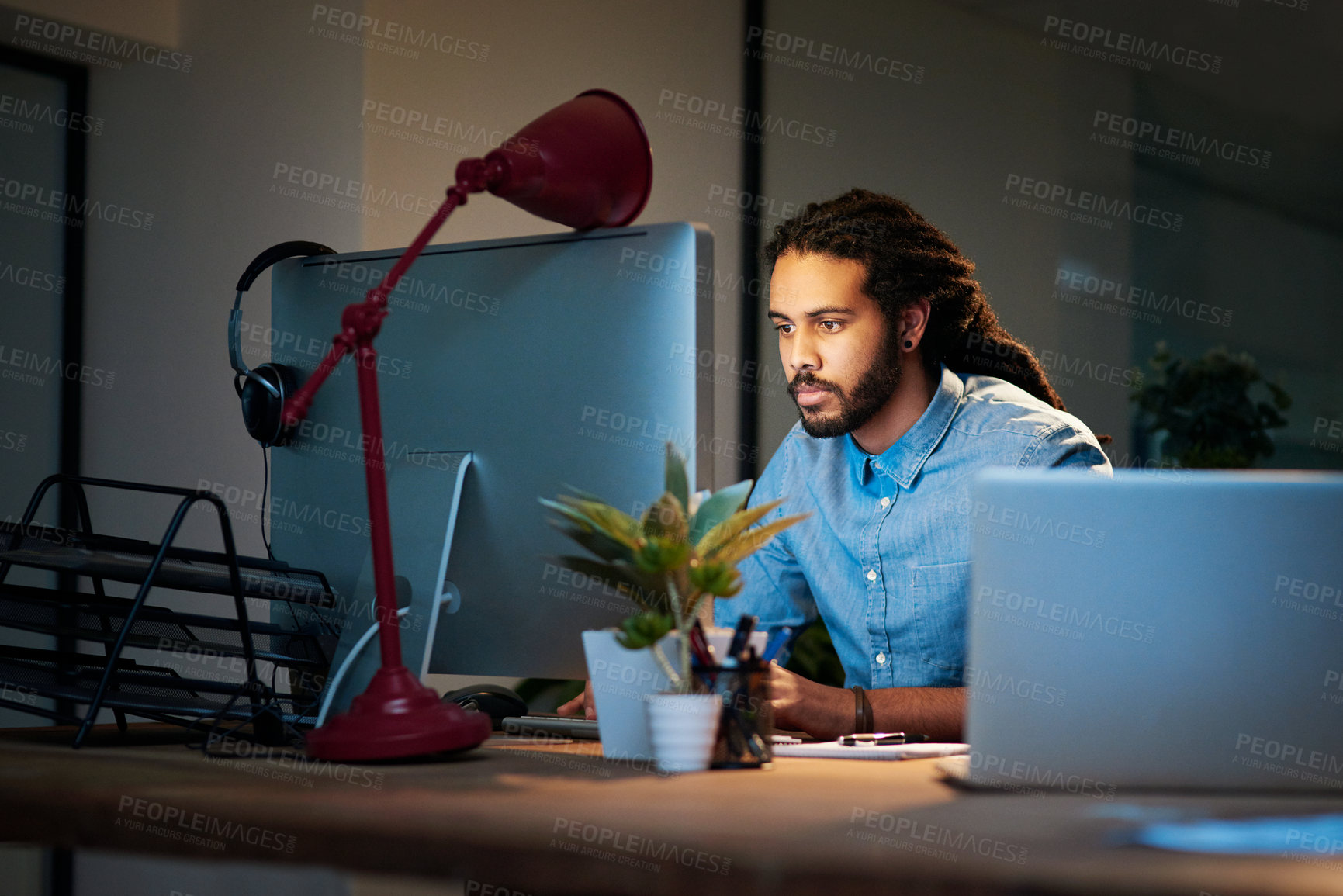 Buy stock photo Cropped shot of a young designer working late on a computer in an office