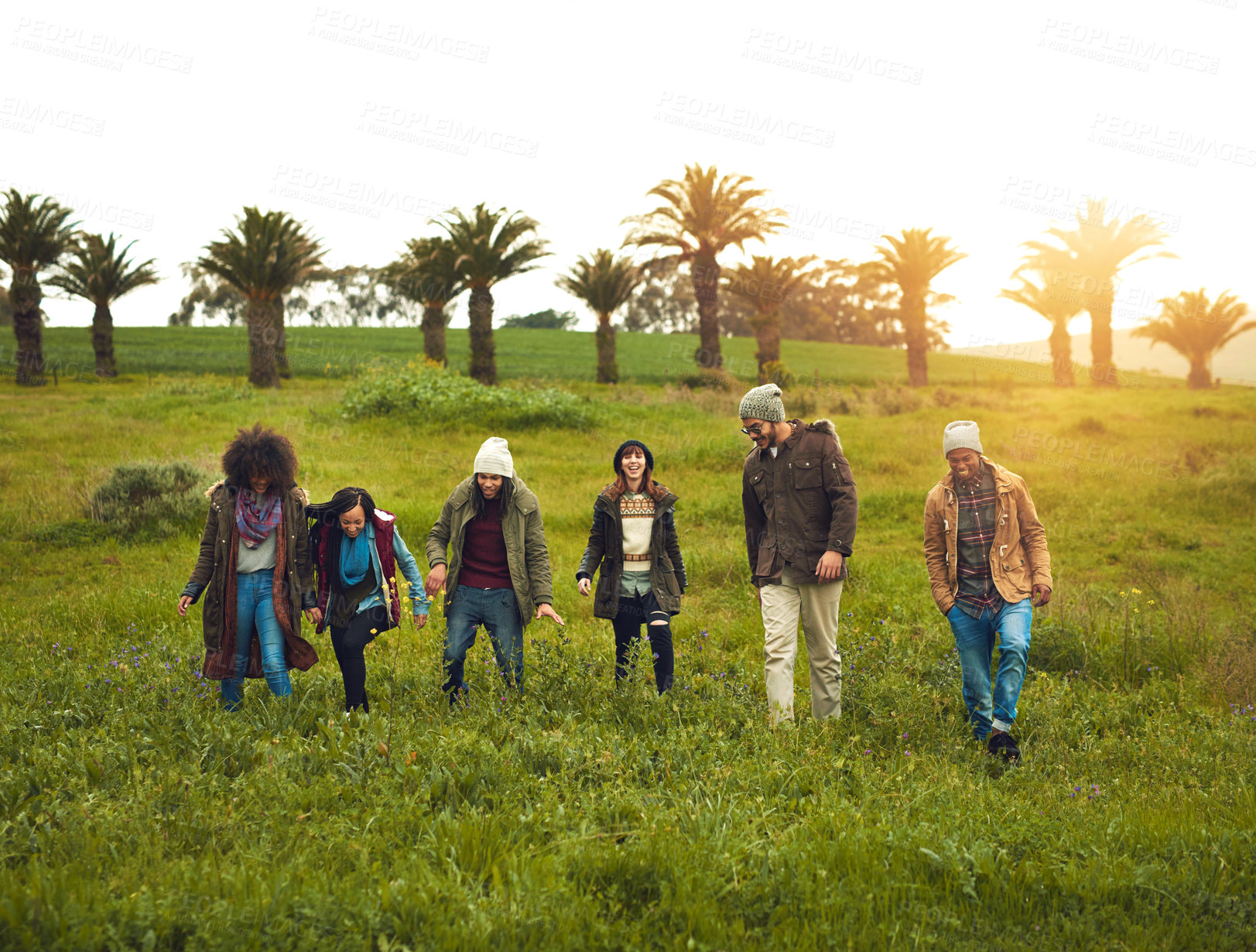 Buy stock photo Walking, field and friends with nature, travel and getaway trip with adventure, countryside and lens flare. Outdoor, people and group with grass, journey and bonding together with happiness or joyful