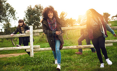 Buy stock photo Shot of a group of friends jumping over a fence in a field for fun