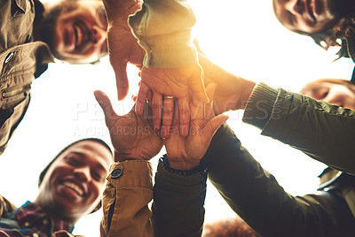 Buy stock photo Low angle shot of a group of friends piling their hands while standing outside