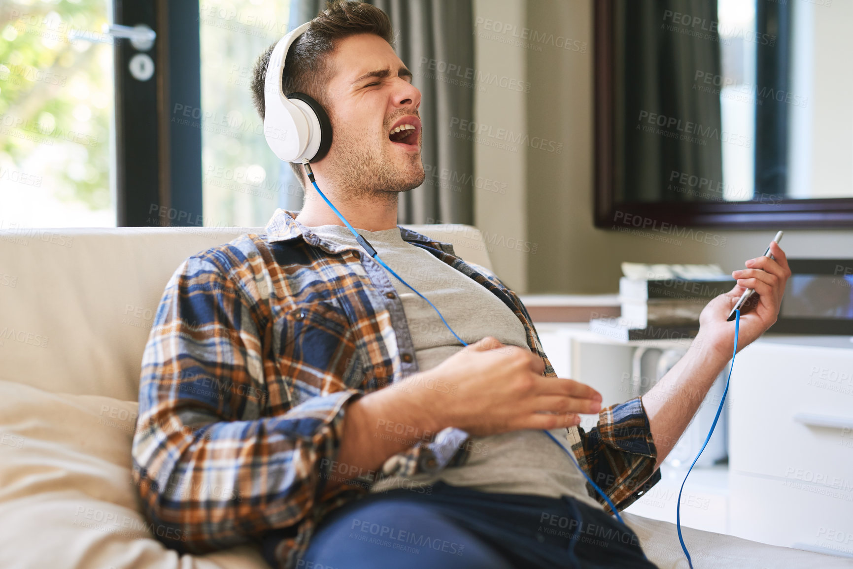 Buy stock photo Shot of a young man listening to music with headphones at home