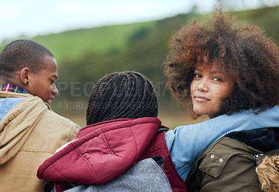 Buy stock photo Portrait of a young woman looking over her shoulder while sitting outside with her friends