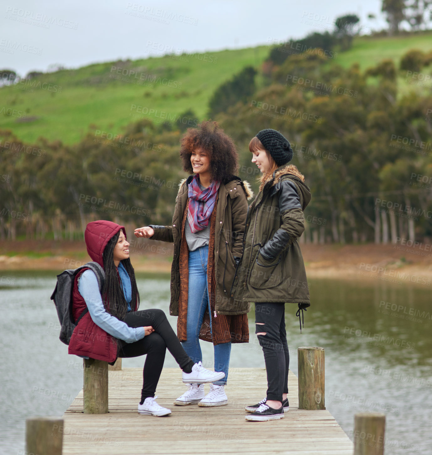 Buy stock photo Happy, women and relax at lake for travel, journey break and camping adventure in nature. Friends, social gathering and chat at river dock for holiday, winter vacation and scenery in countryside