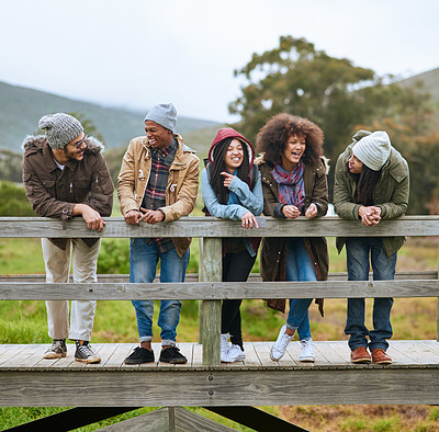 Buy stock photo Shot of a group of friends hanging out on a wooden bridge together