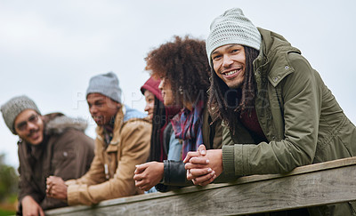 Buy stock photo Portrait of a happy young man hanging out on a wooden bridge with his friends