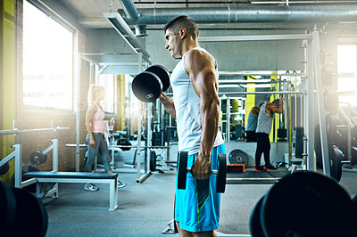 Buy stock photo Shot of a young man working out alone in the gym