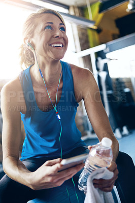 Buy stock photo Shot of a sporty woman taking a break between workouts