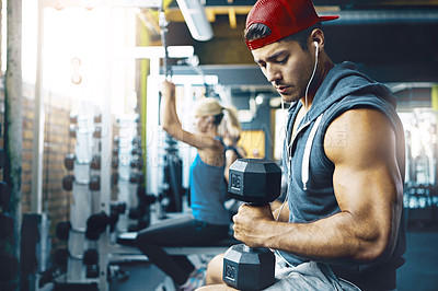 Buy stock photo Shot of a young man working out alone in the gym