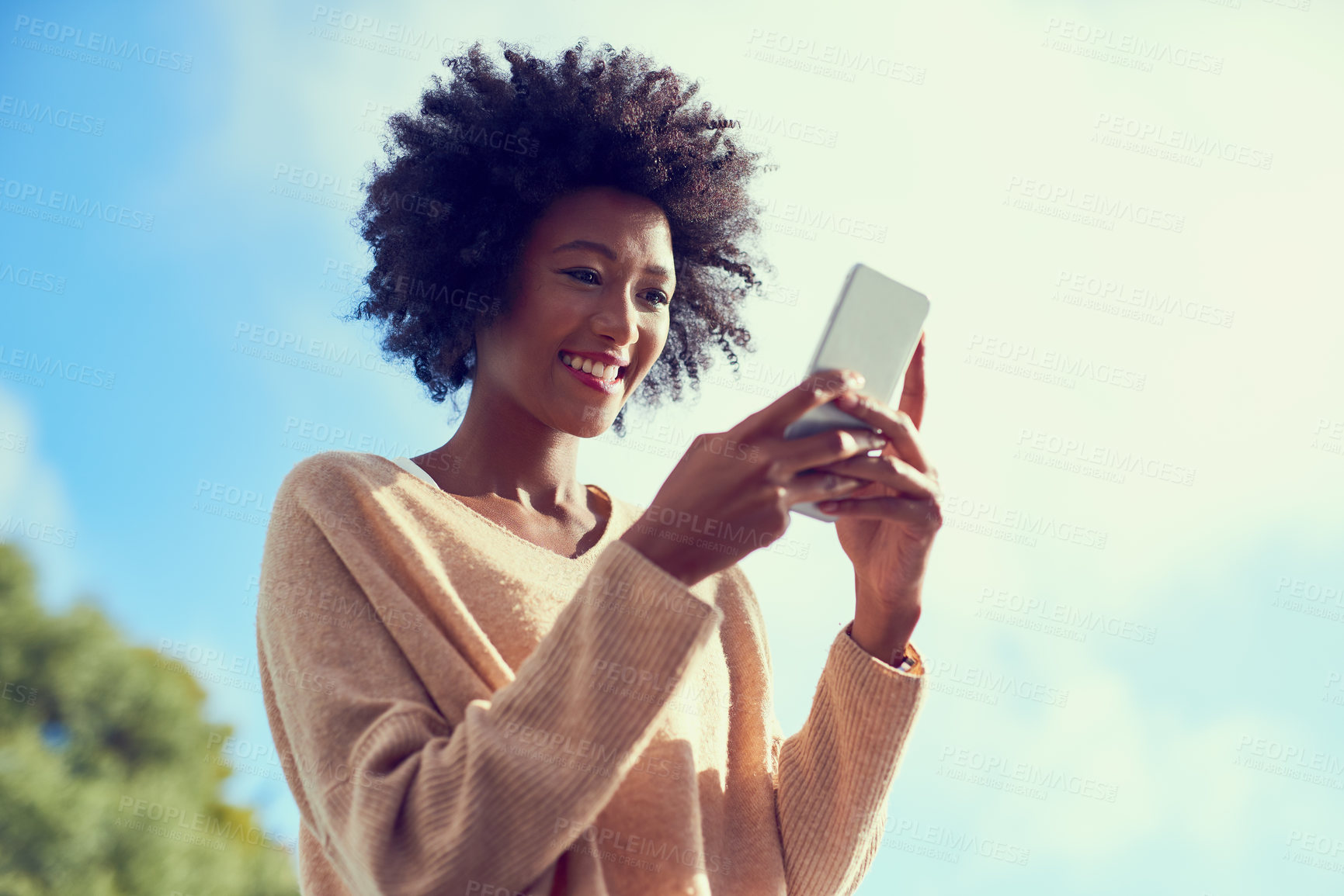 Buy stock photo Shot of a young woman using her phone outside