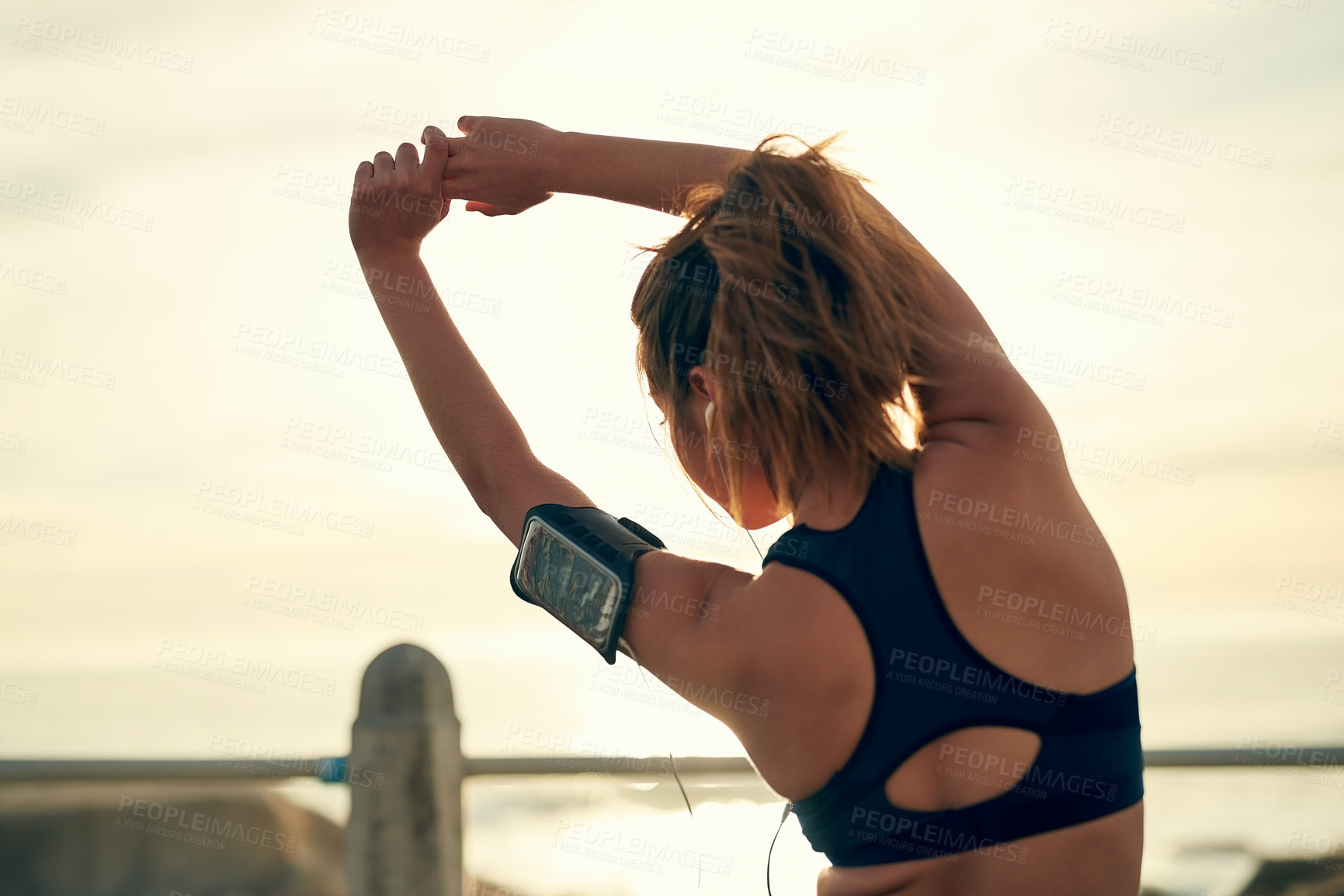 Buy stock photo Girl, runner and stretching arms at beach, outdoor and warm up for exercise or fitness training. Female person, back and athlete for cardio preparation, muscle flexibility and music for workout