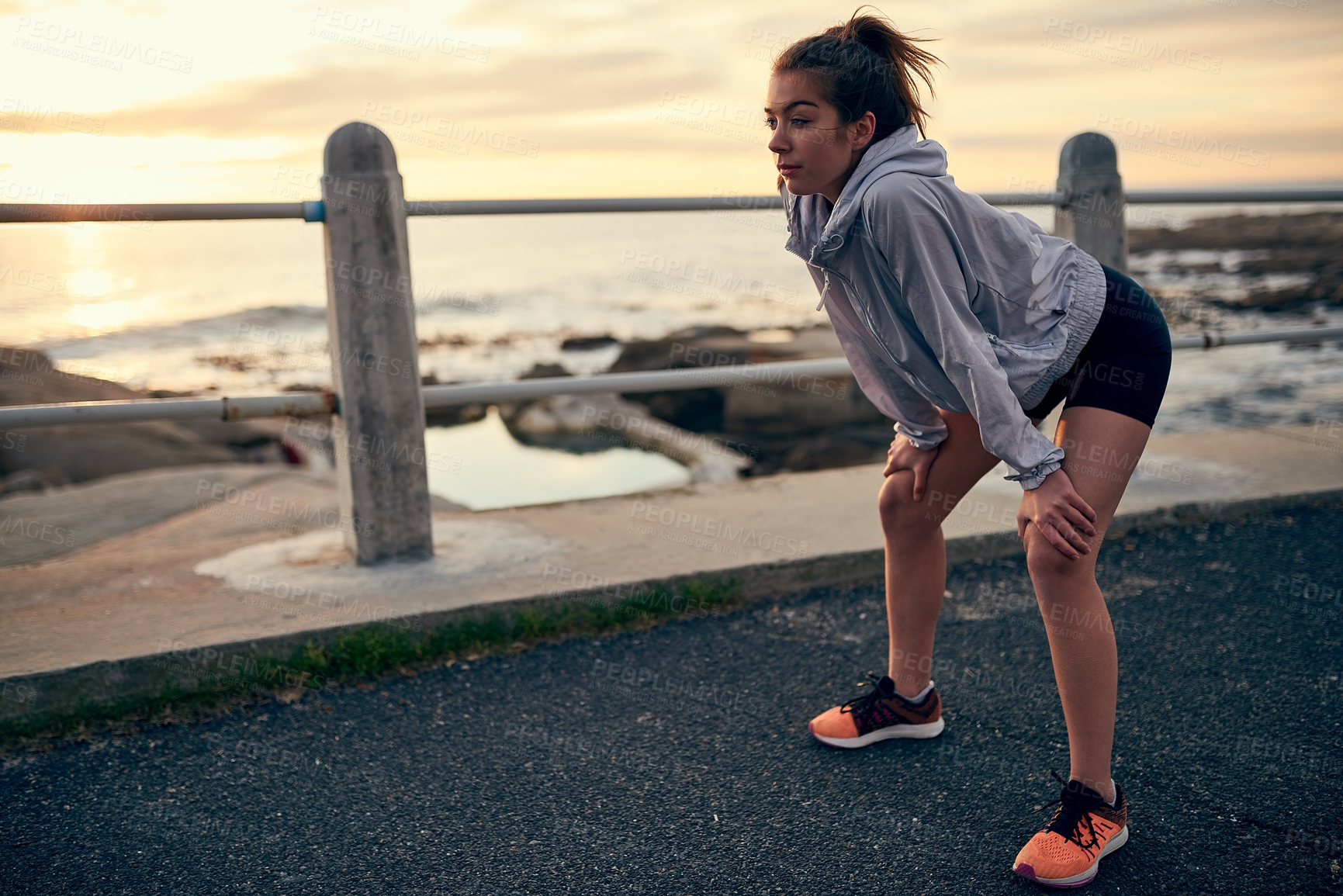 Buy stock photo Sunset, woman and tired at beach for fitness, exercise and break in summer. Female runner, breathe and athlete in nature for workout, marathon training and ocean with rest for health and wellness