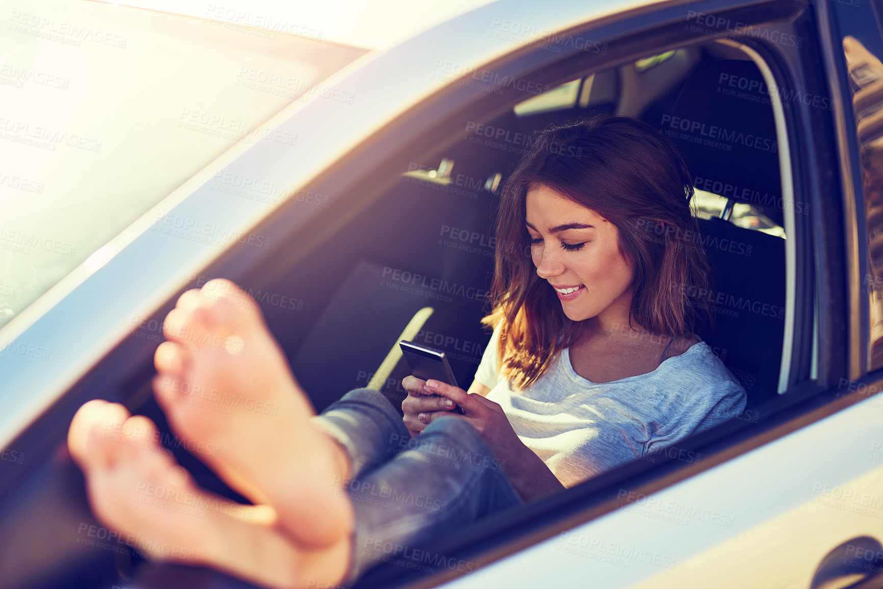 Buy stock photo Shot of a young woman sending a text message while sitting in her car