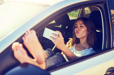 Buy stock photo Shot of a young woman taking a selfie while sitting in her car